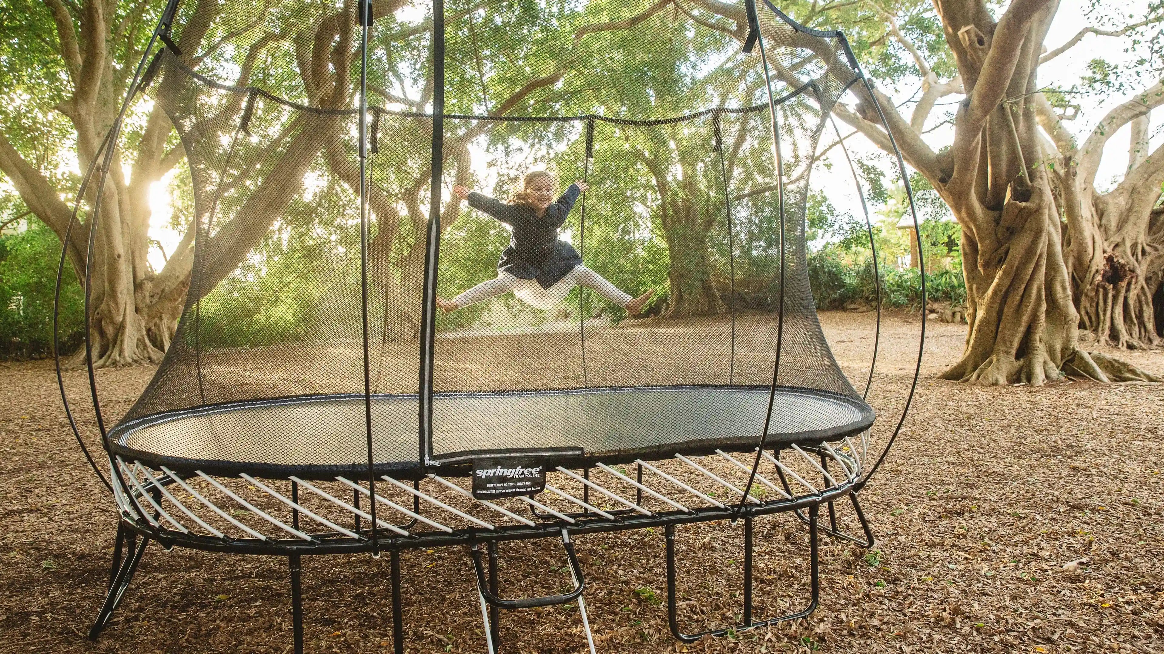 young girl jumping high on an outdoor trampoline