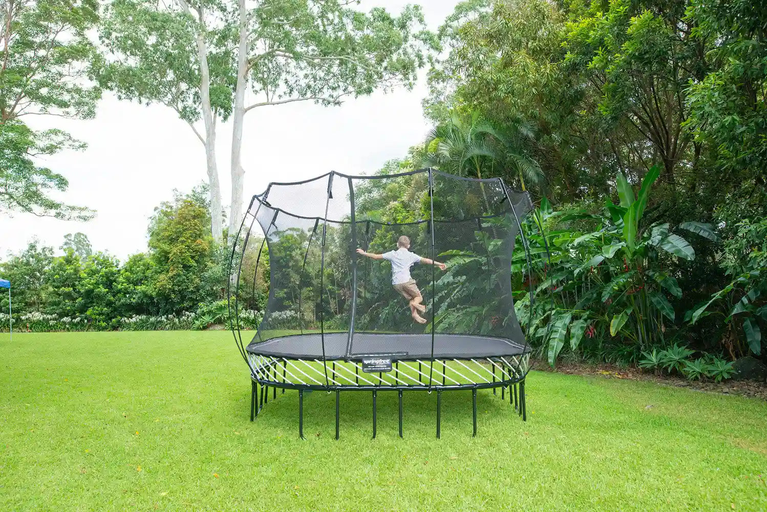 a boy jumping on an outdoor trampoline